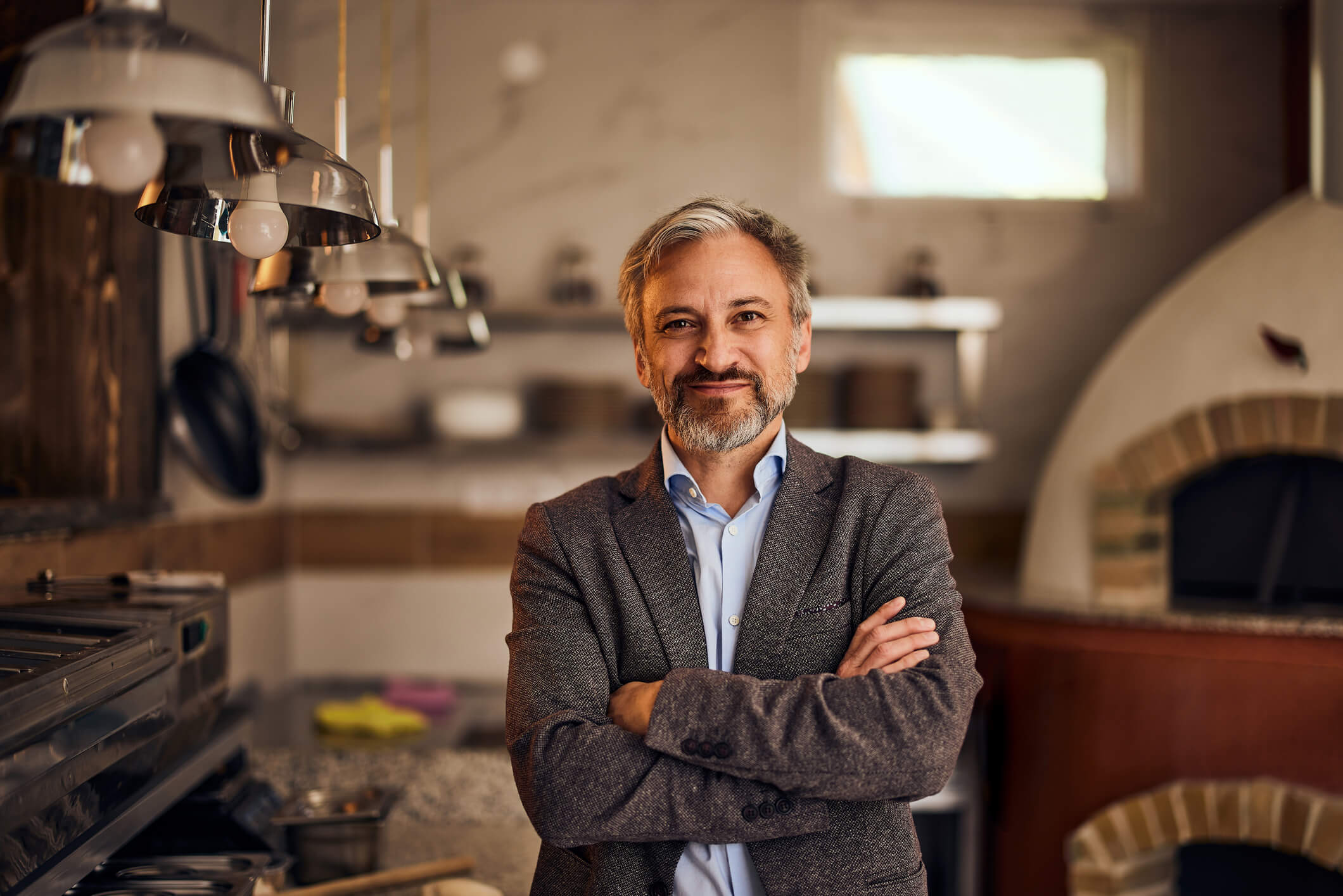 male business owner in suit standing in front of pizza kitchen