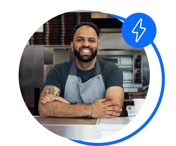 A chip shop owner smiles at his counter. He's happy after sorting his business gas contract.
