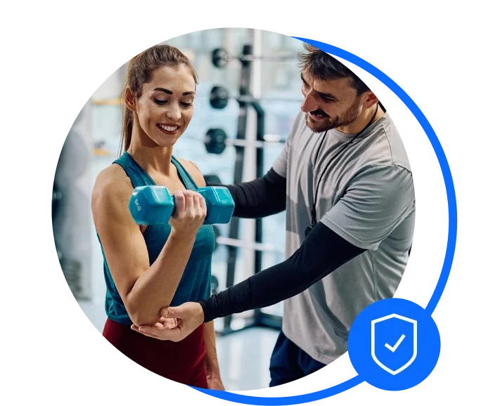 Male personal trainer helping a female in the gym do a bicep curl with a 2kg weight