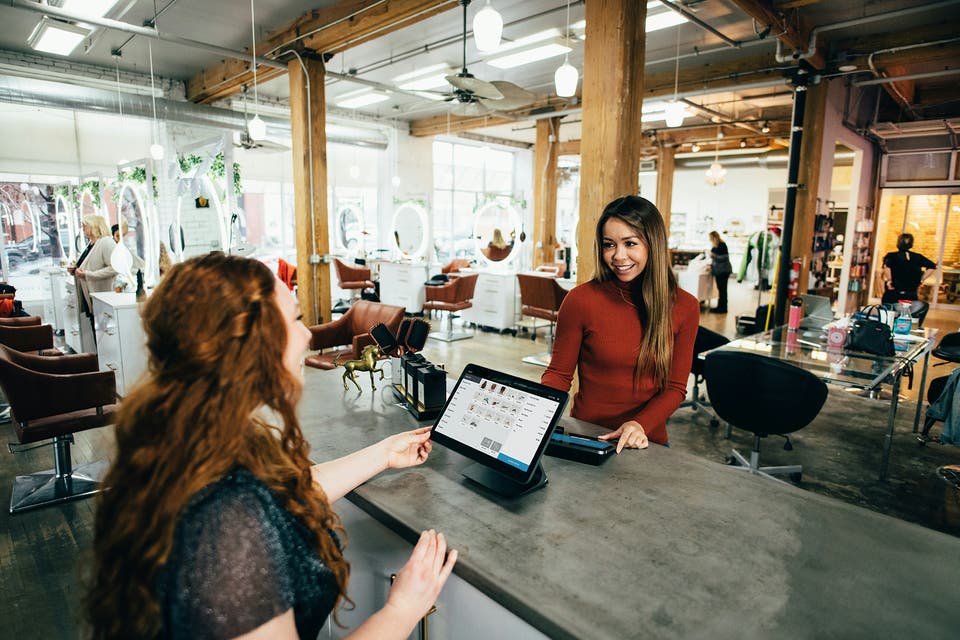 A woman in a red top at a till in a fancy salon