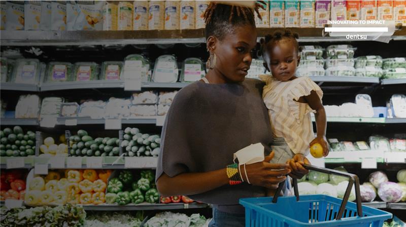 A picture of a mother holding a young child in front of a supermarket aisle