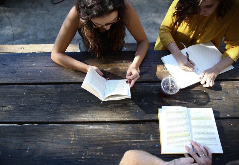Students reading outside on a bench