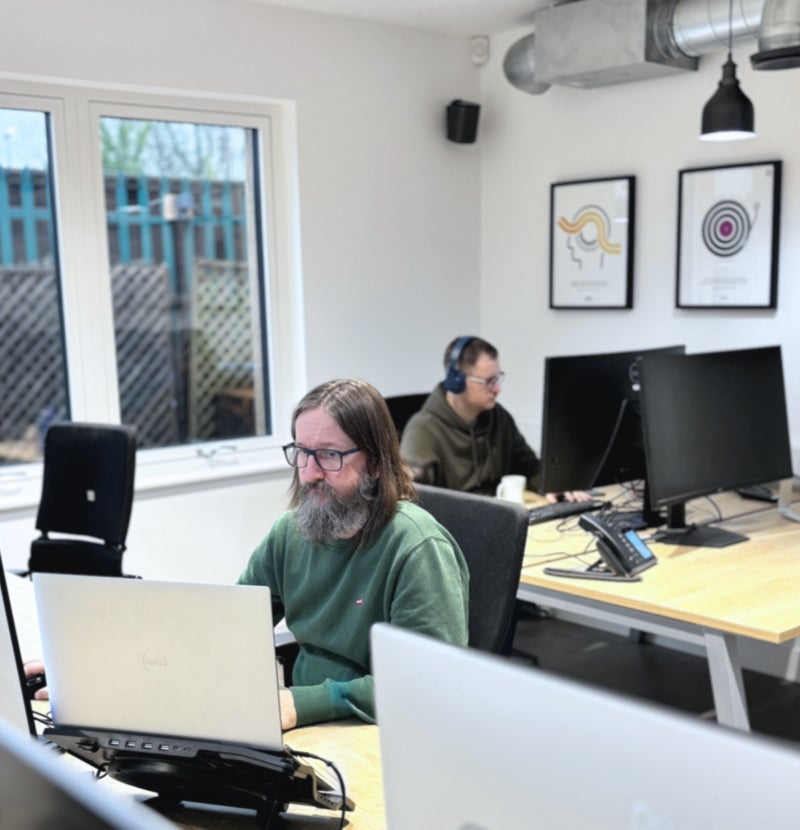 Two members of the team hard at work at their desks.