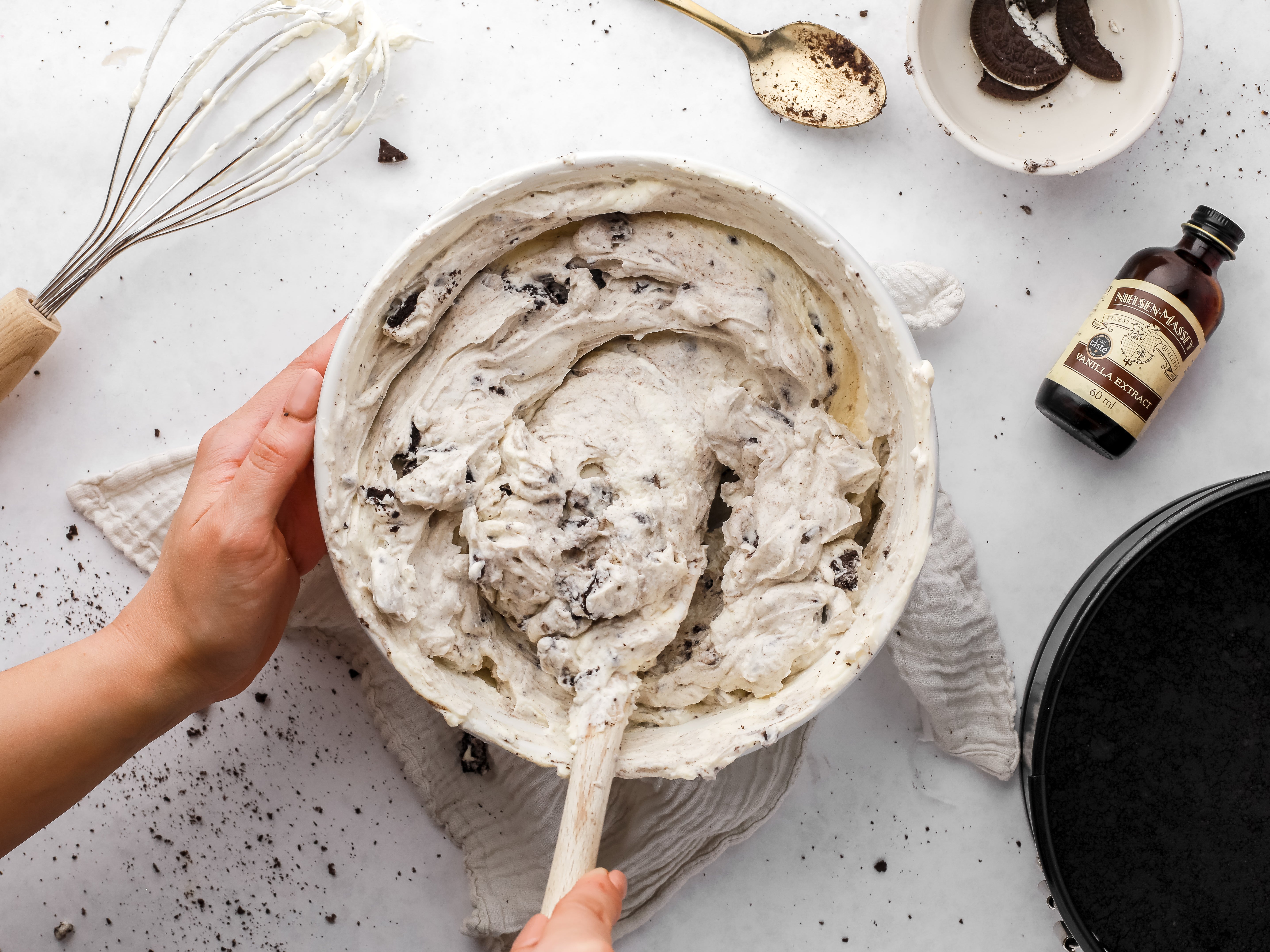 Hand mixing cheesecake ingredients in a bowl with a spatula