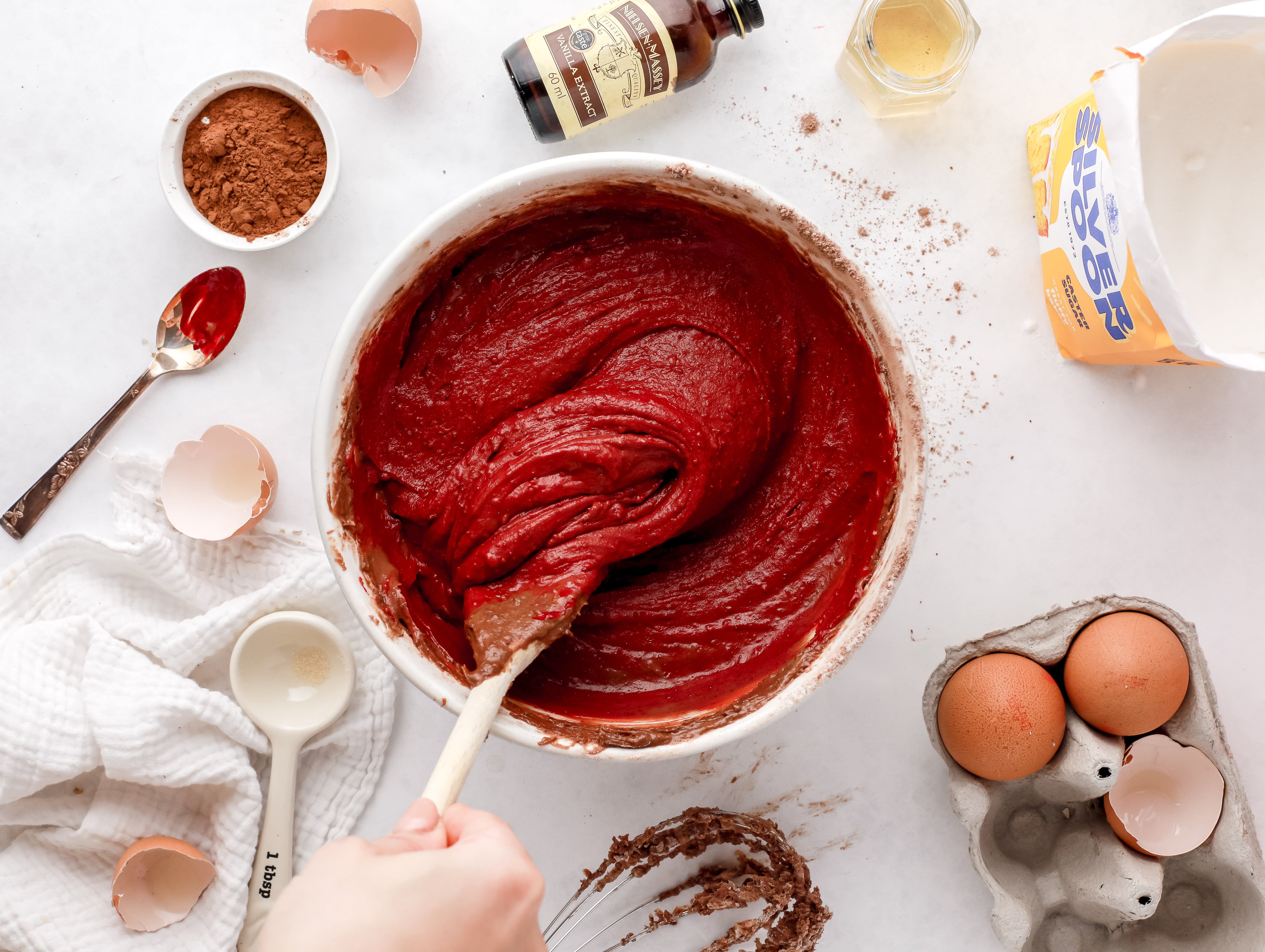 Red cake mixture being stirred in a bowl