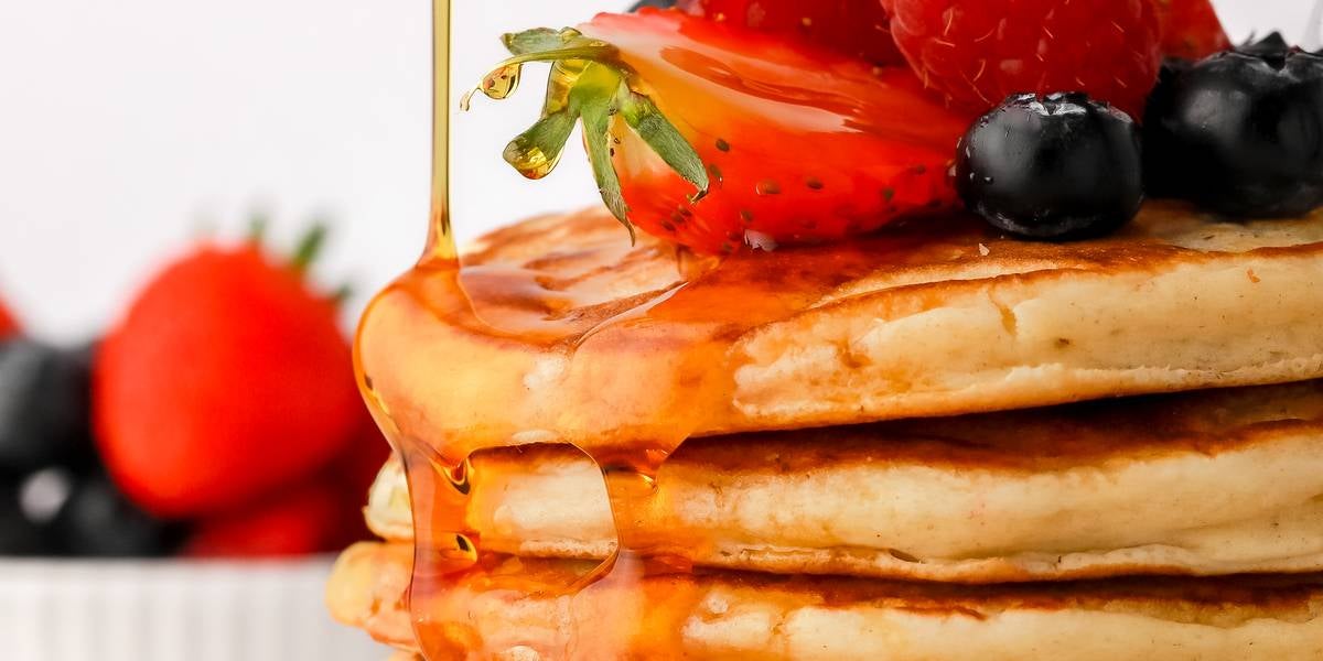 Fresh American pancakes being drizzled with maple syrup
