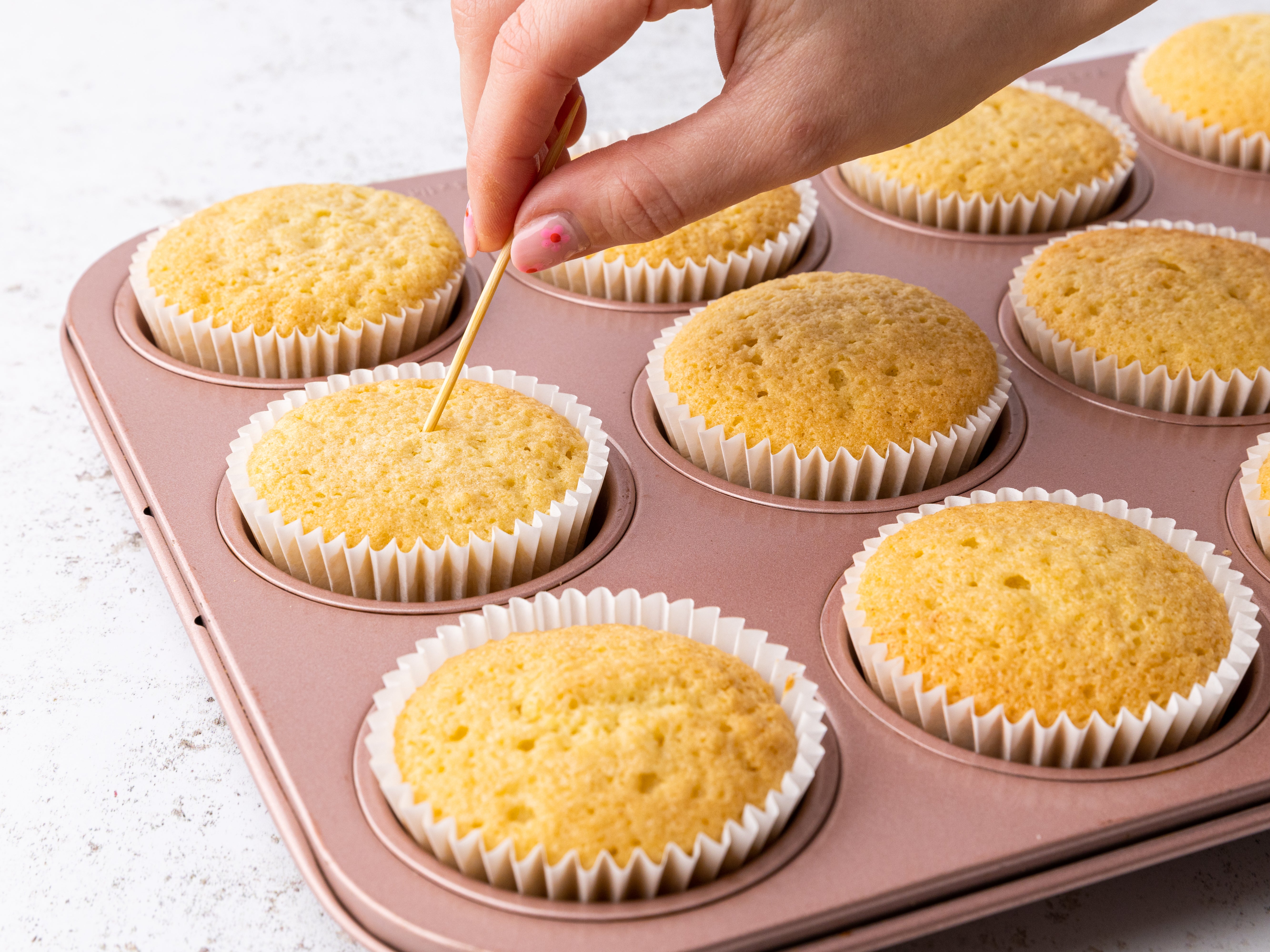 Skewer being inserted into a cupcake to check it has been baked
