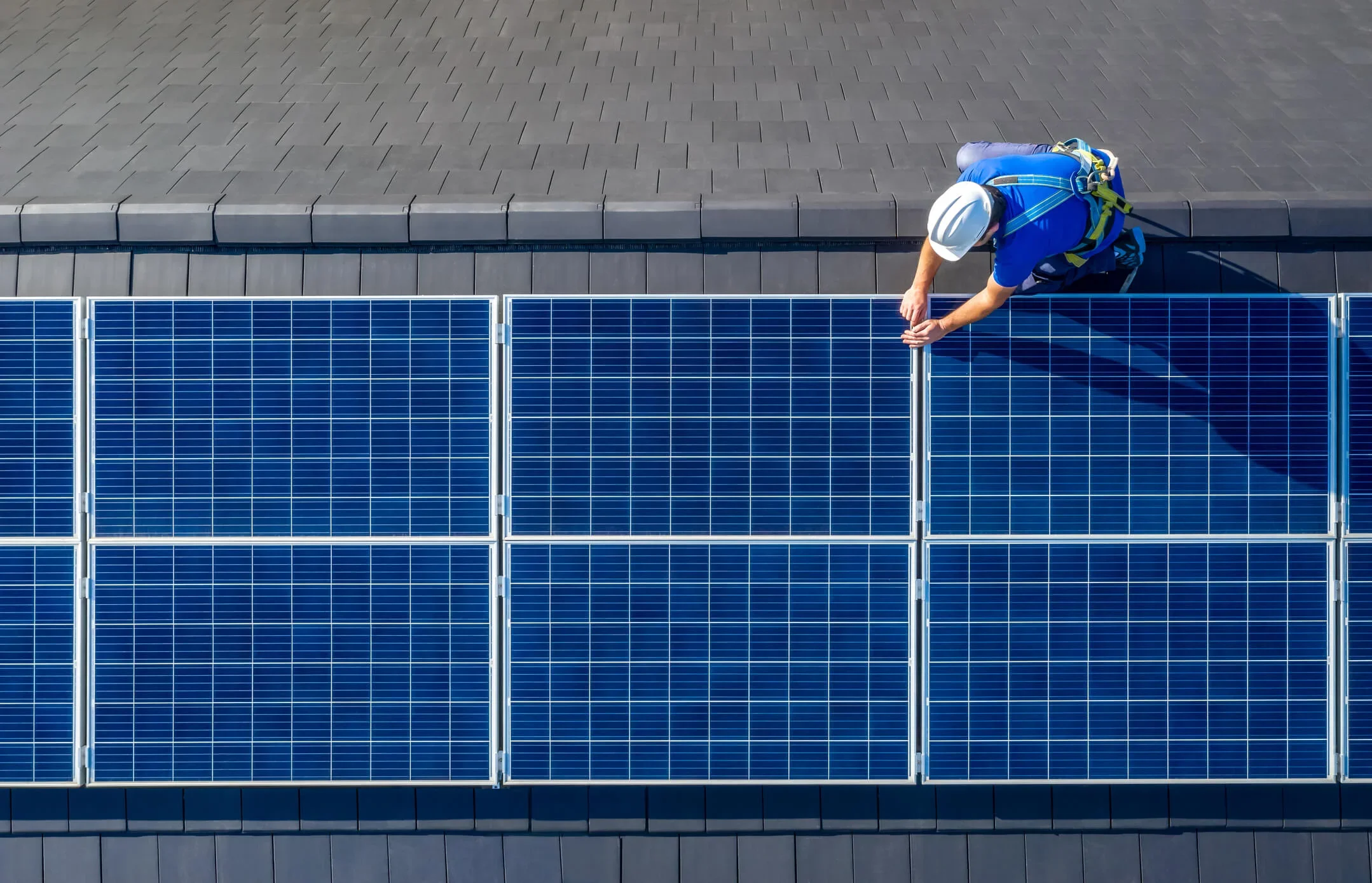 An engineer fits solar panels to a business building. Energy produced can be sold via the Smart Export Guarantee.