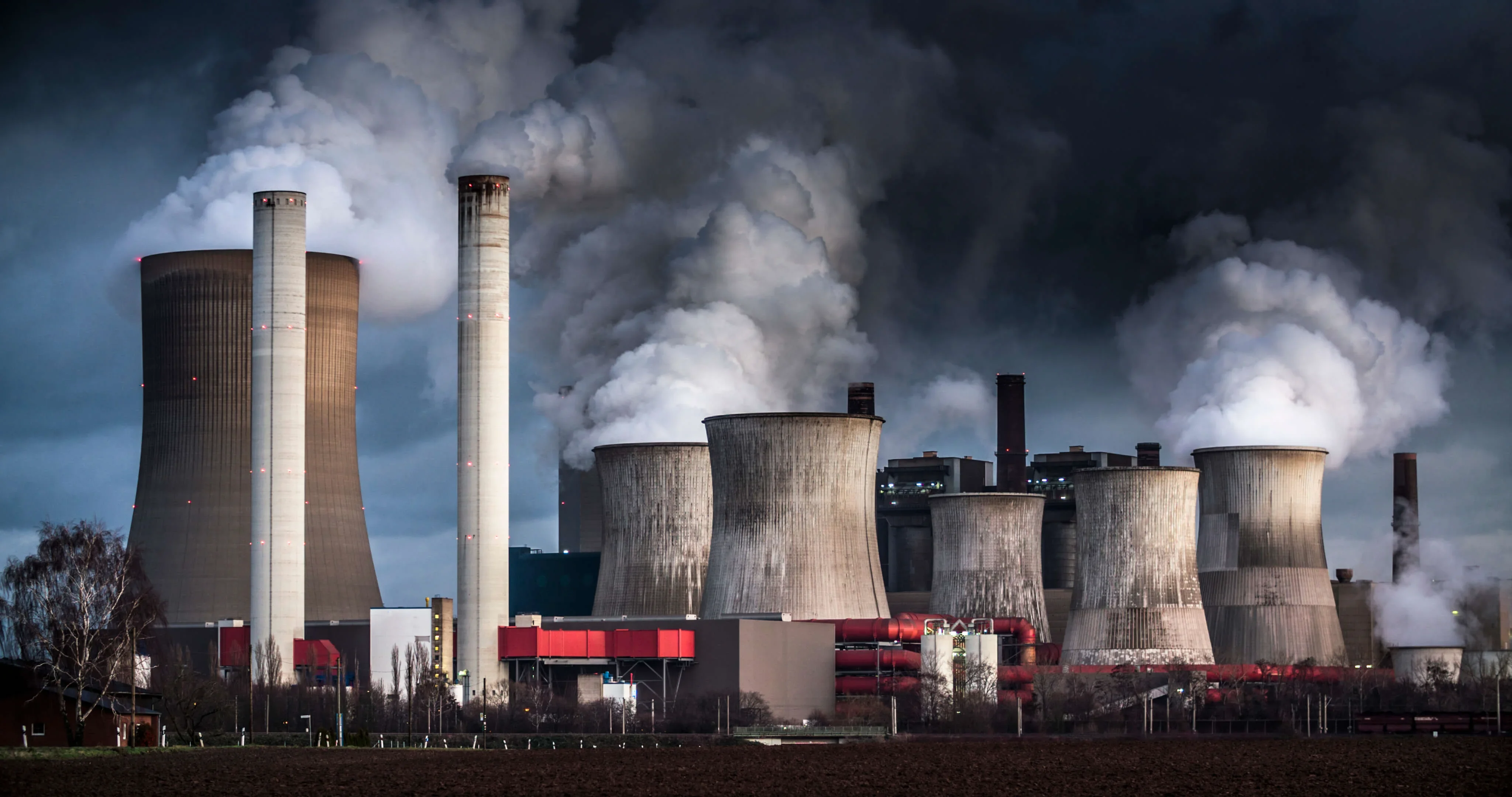 Large chimney stacks from an industrial plant blow smoke into the atmosphere.