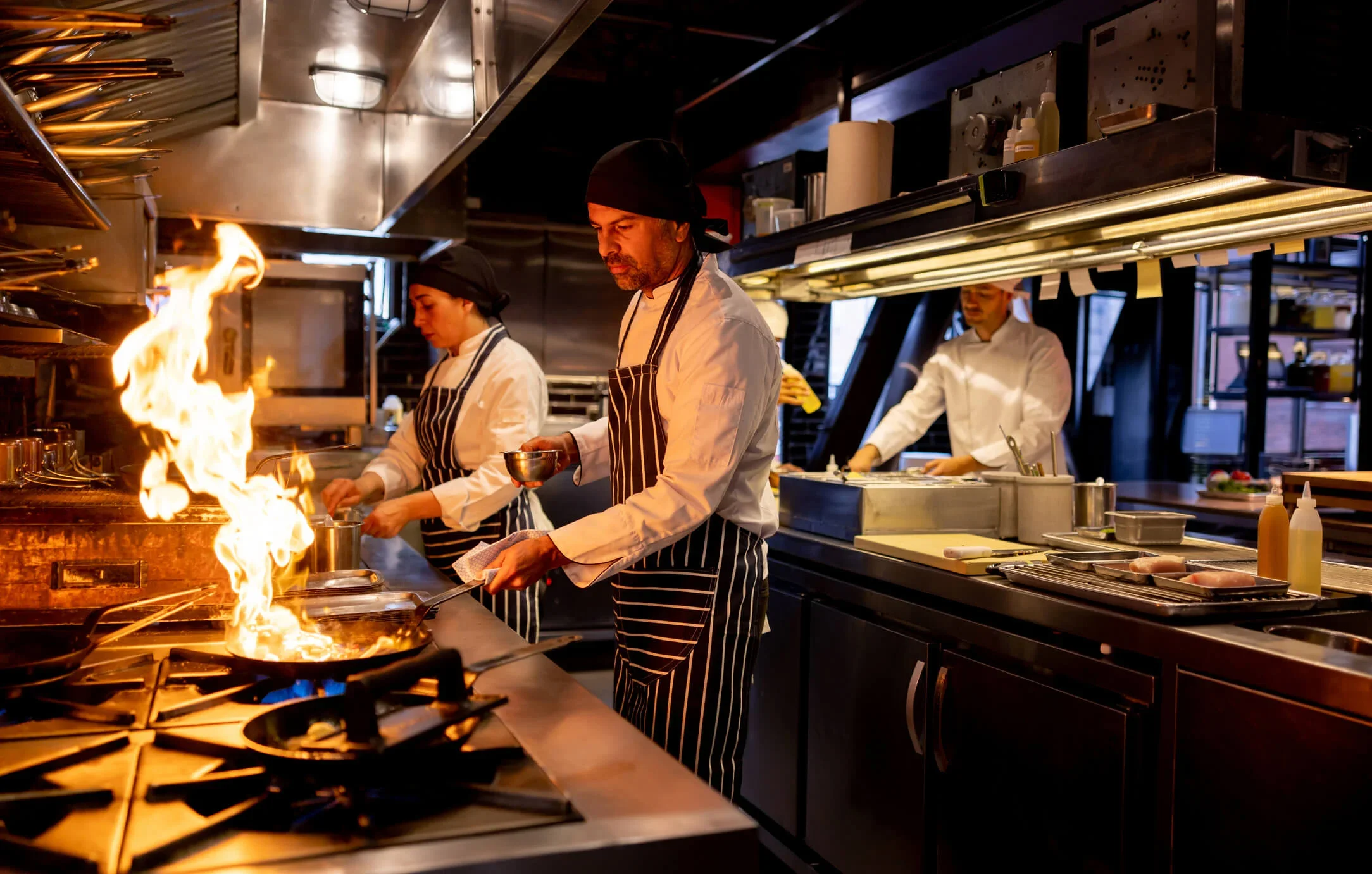 Chef cooking at a restaurant and flaming the food on a pan
