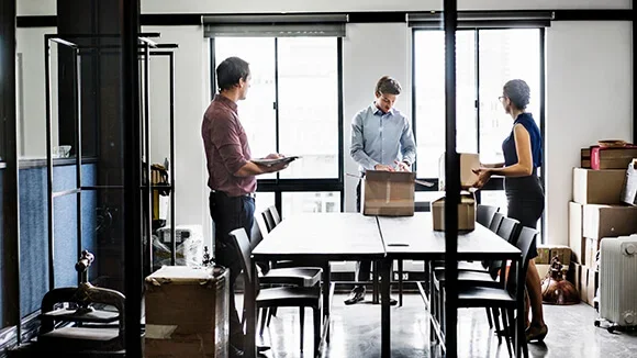 A business owner and two employees unpack boxes as they settle into their new business premises