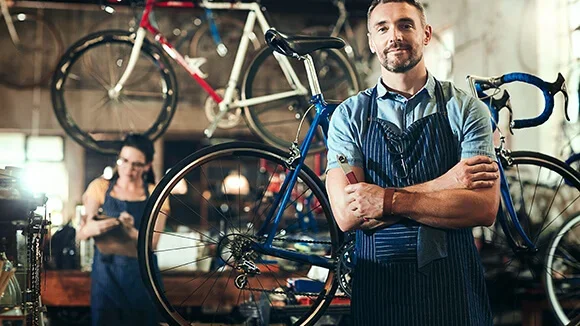 A small business owners stands in his bicycle repair shop