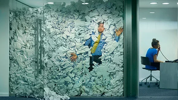 An office worker is trapped in an office full of paper energy bills to represent the confusing number of business energy tariffs available.
