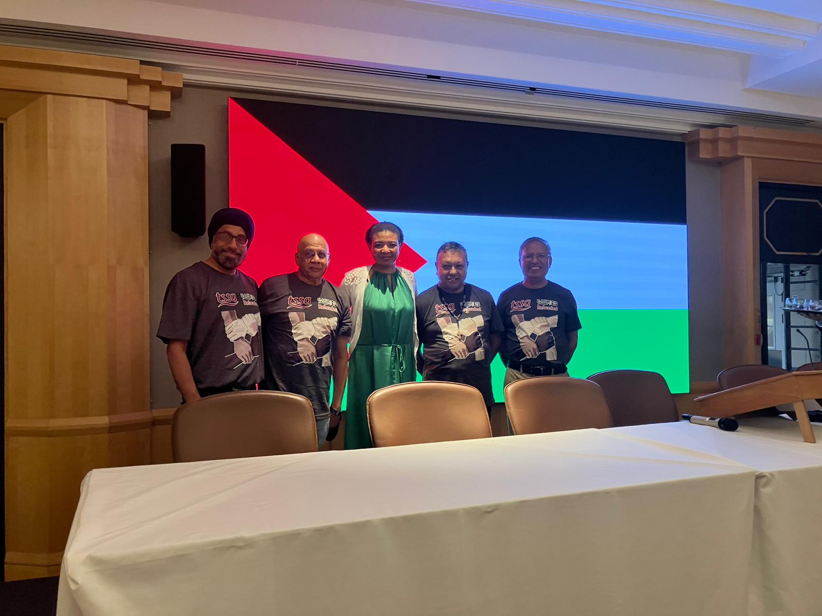 Five E-Mix members standing in front of the flag of Palestine, at our solidarity event. 
