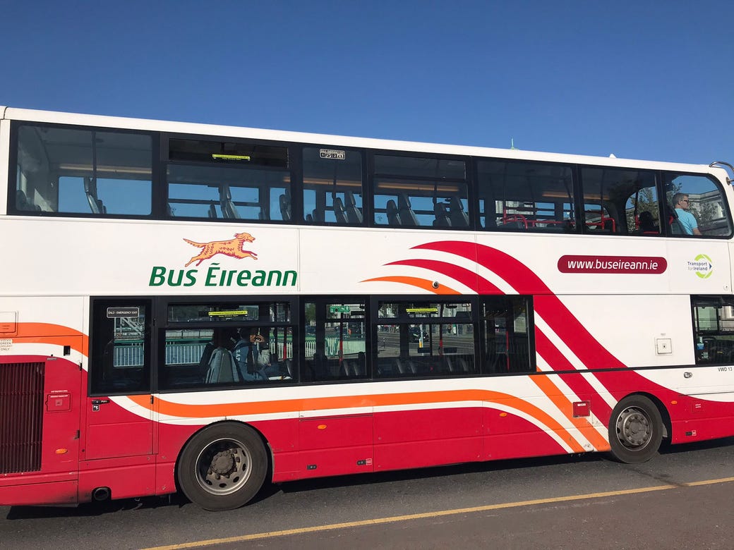 A double decker bus in white and red livery with a logo of a jumping Irish red setter and the words Bus Éireann in green. 