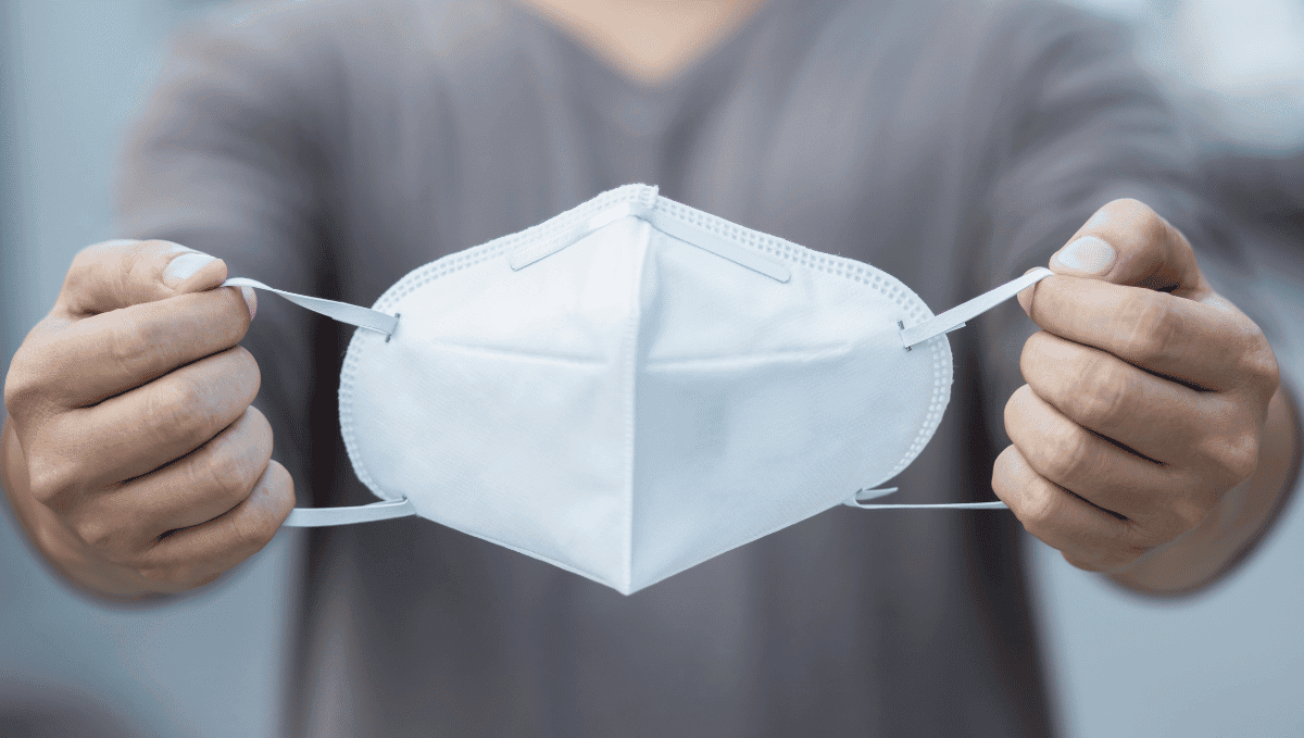 Man holding a white face mask in two hands.