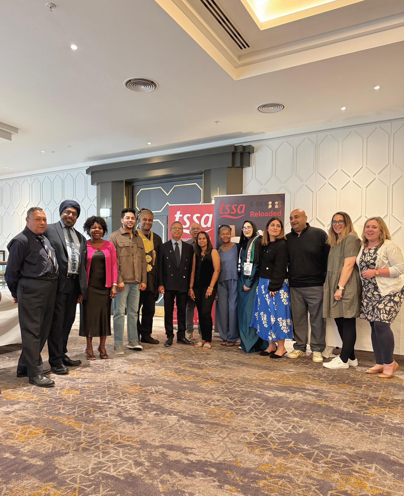 E-Mix members at TSSA Annual Conference in Belfast. There are 14 members standing in front of the TSSA and E-Mix banners, outside the conference hall. 