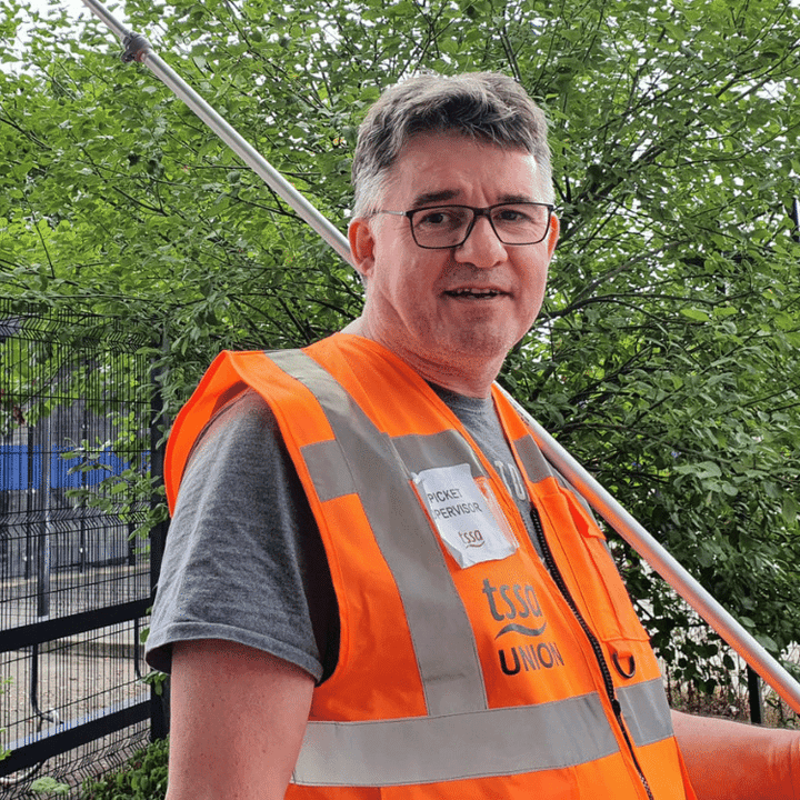 Tim in orange high vis jacket holding a flag