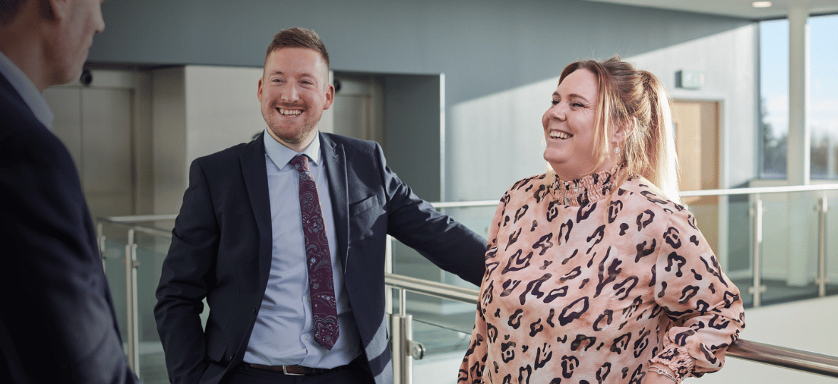 A male and female business development manager talking and smiling in a office hall
