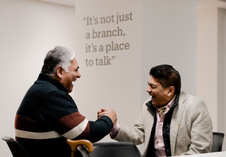 Two men shaking hands and laughing.