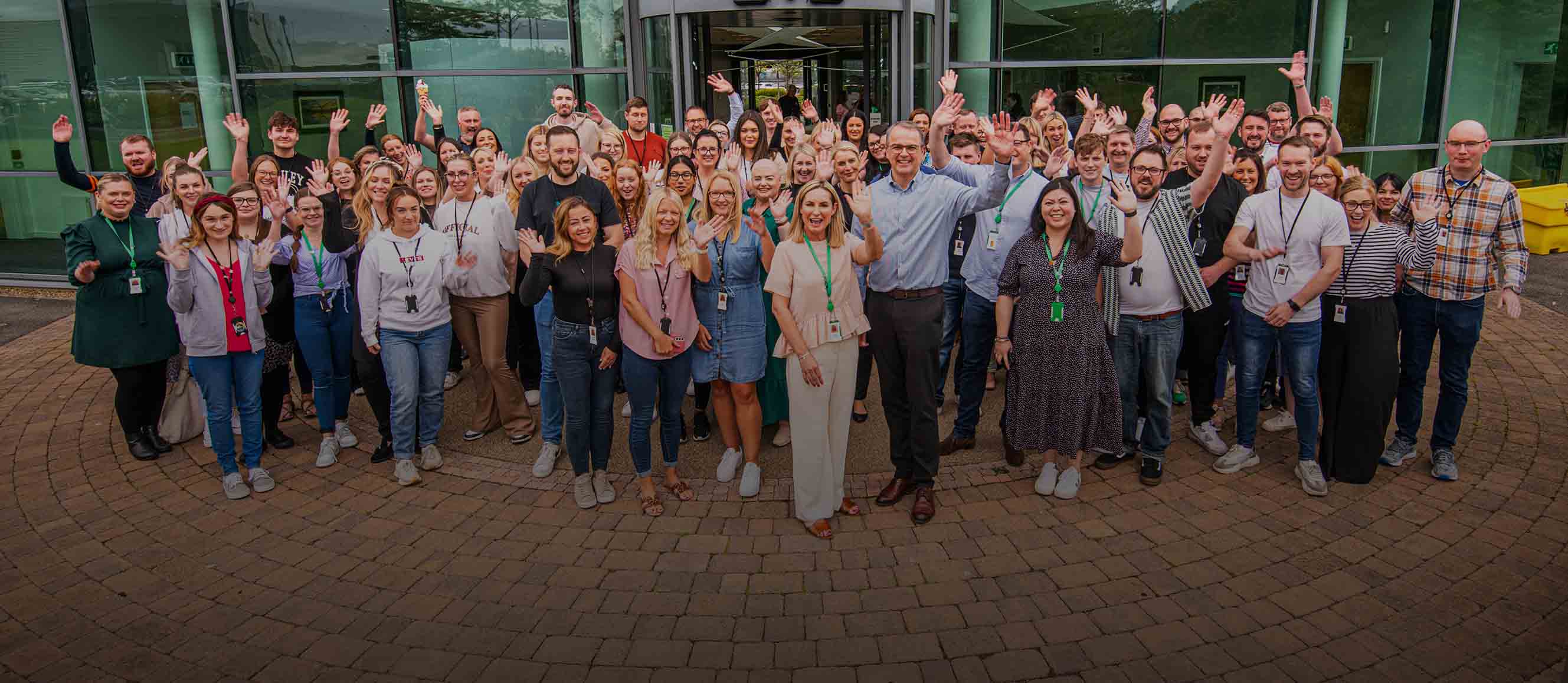 Newcastle Building Society colleagues stood outside of the head office, waving and smiling. 