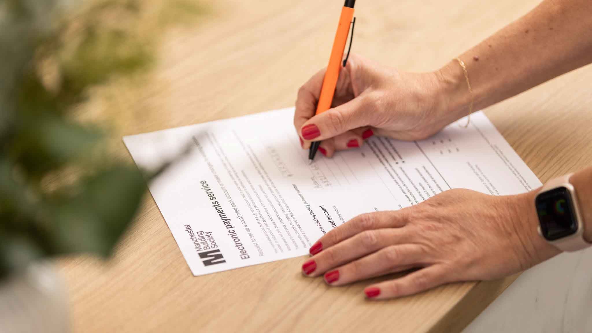 A person writing on a paper application form. 