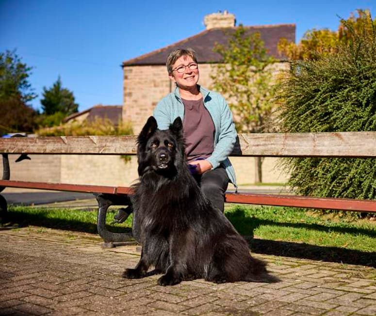Lady on bench sat with dog.