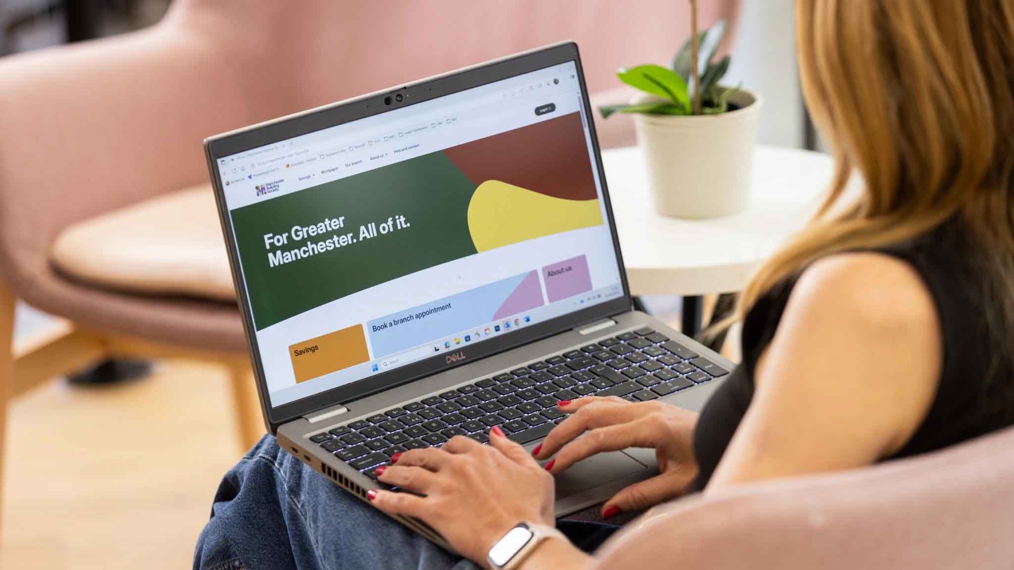 A person using a laptop with the Manchester Building Society website on the screen.