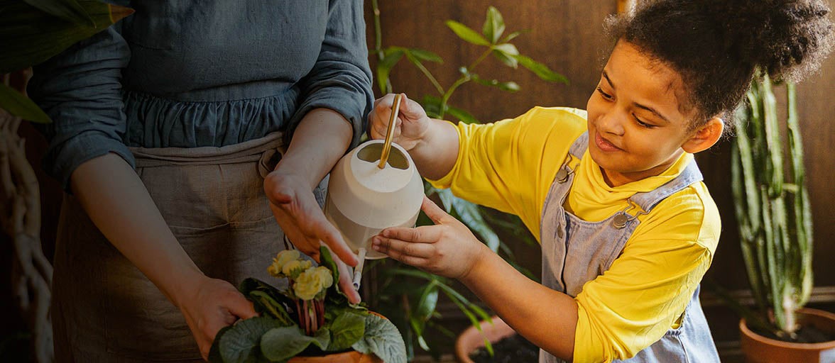 Little girl watering a plant in the garden. 