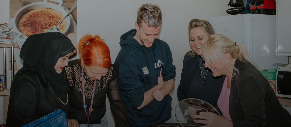 A group of people looking at something in a kitchen.