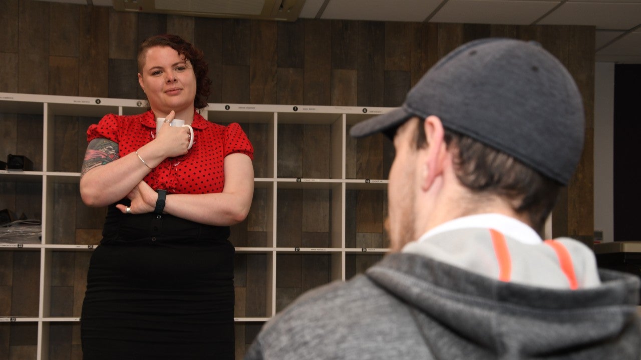 A woman stood with a mug in her hand chatting to a man.