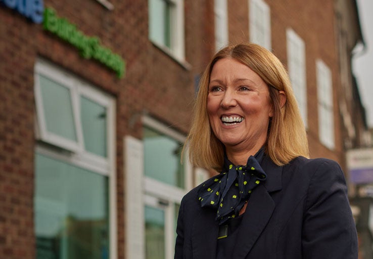A woman smiling in front of Yarm's Newcastle Building Society