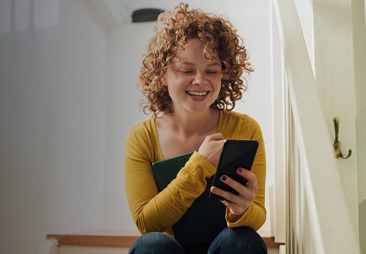 A woman sitting on some stairs holding a phone