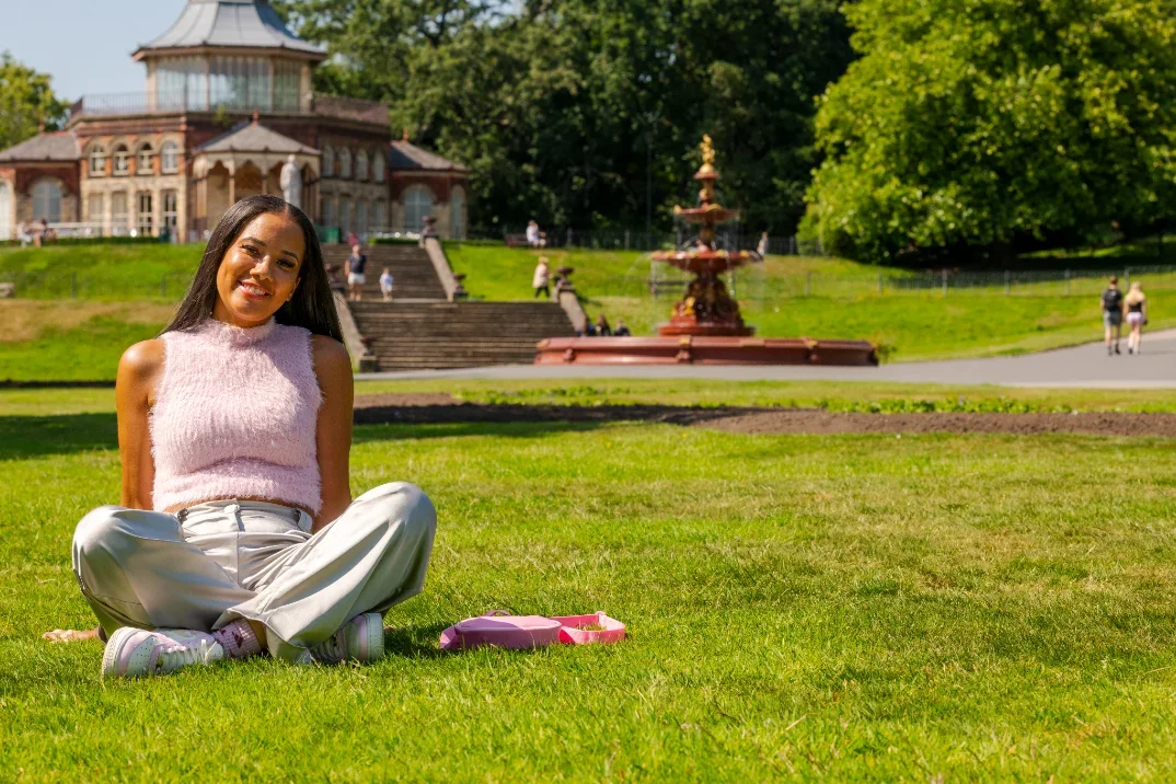 A woman in a pink top sitting on the grass in Wigan.