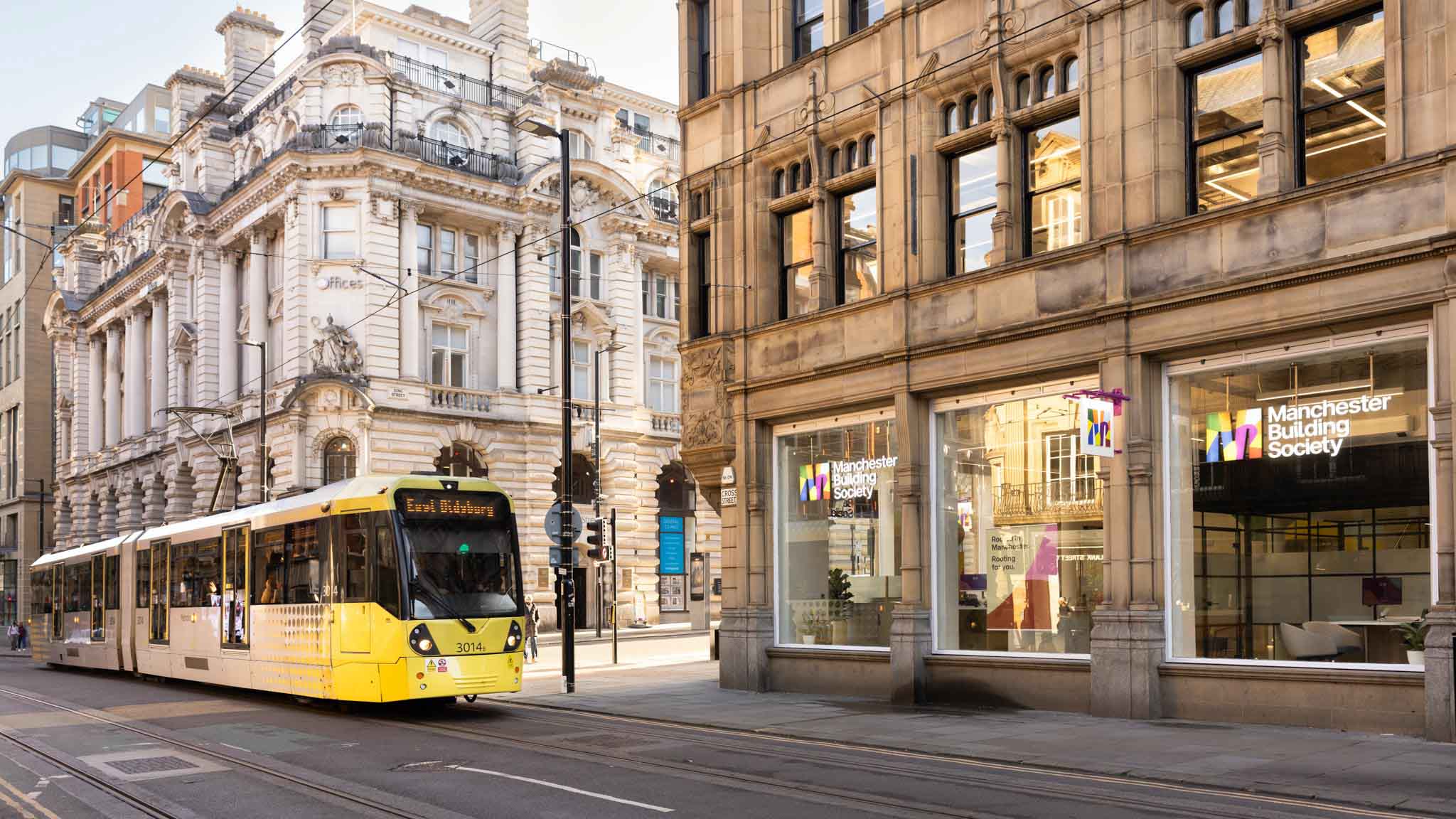 A yellow bus on Cross Street, outside the King Street Manchester Building Society branch. 