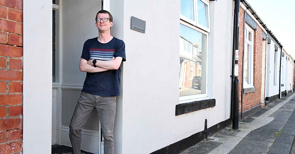 A man stood in his doorway of his home. 