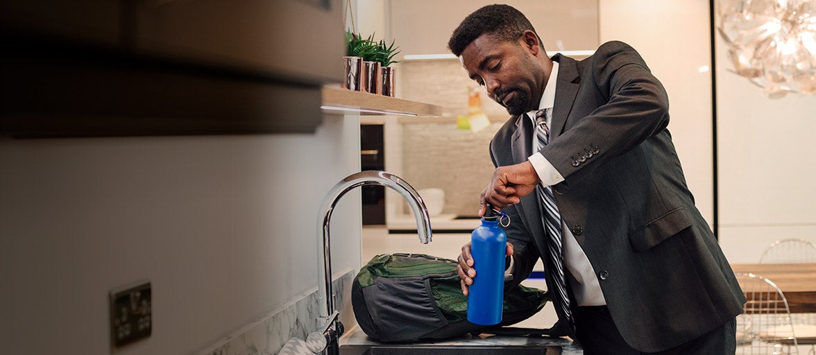 Man at home filling up his water bottle.