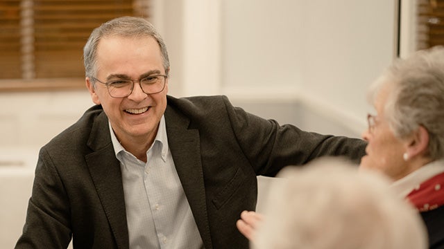 A man in a suit and glasses smiling