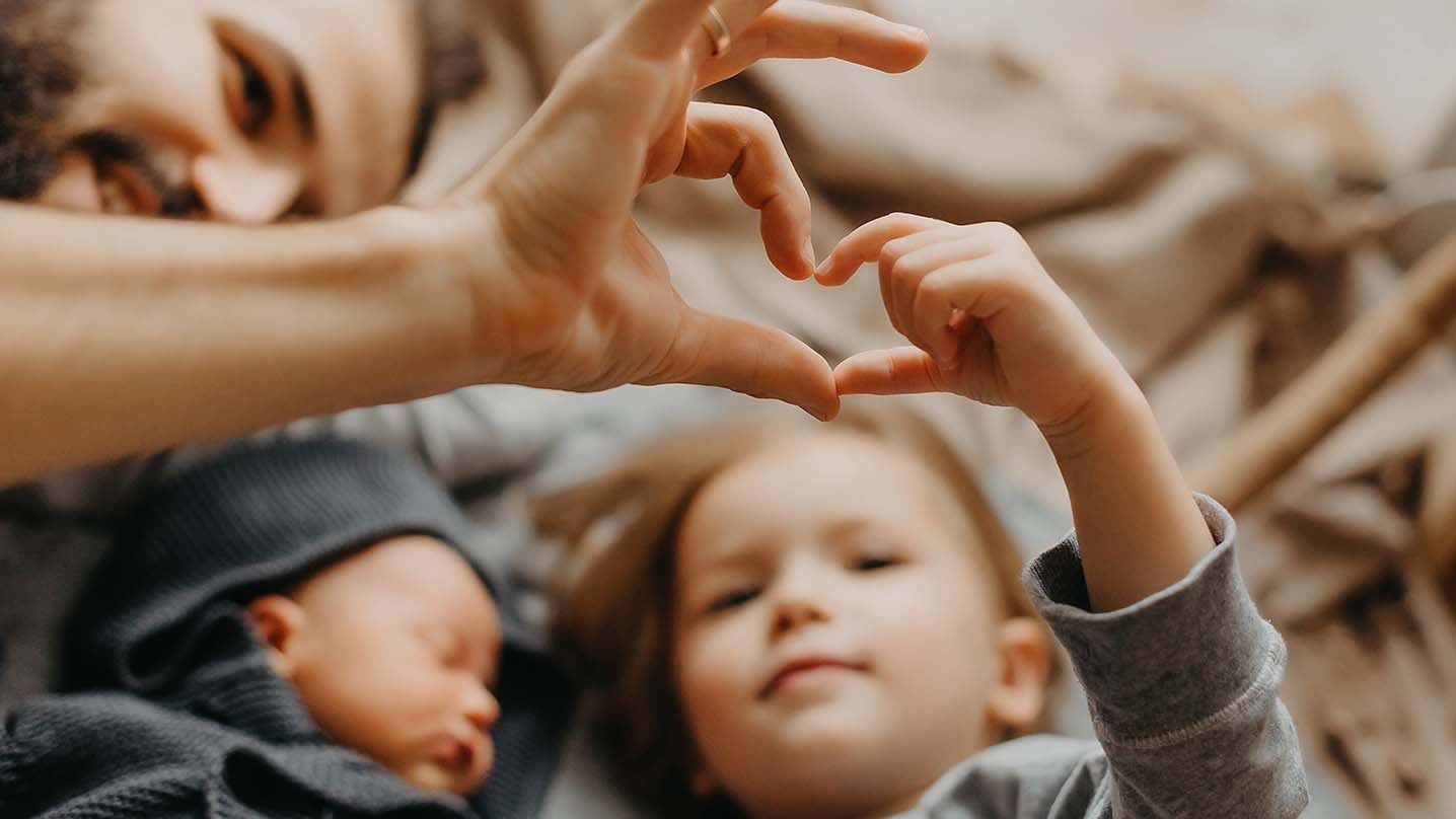 A father and his children, making a heart with their hands.