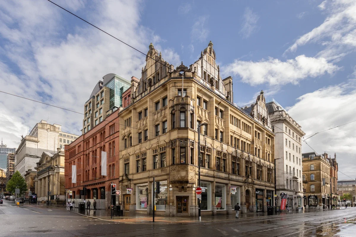 A street corner view of Manchester Building Society with buildings and people walking on it