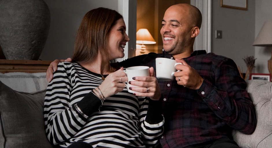 Man and woman having a cup of coffee on the sofa.