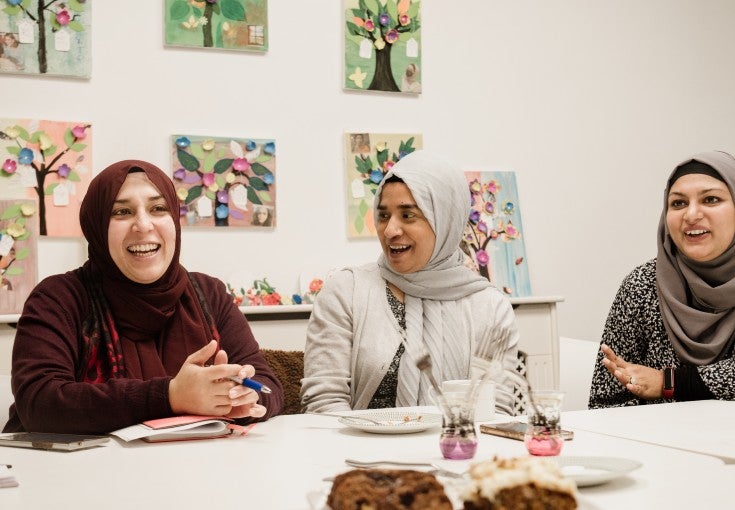 Three ladies chatting and laughing with each other at Apna Ghar.