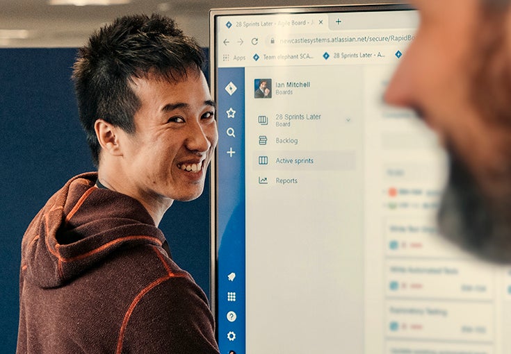 A man smiles in front of a screen