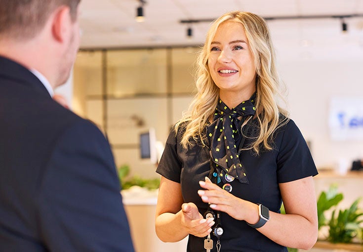 A branch colleague stood smiling and talking to a customer. 
