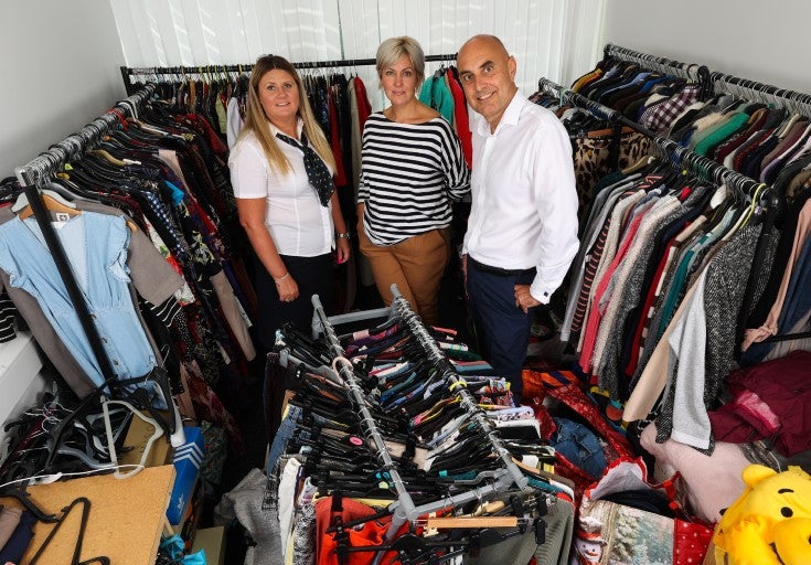 Three people amongst the clothing rails at Age UK Teesside.