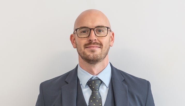 Man smiling, wearing a suit and glasses