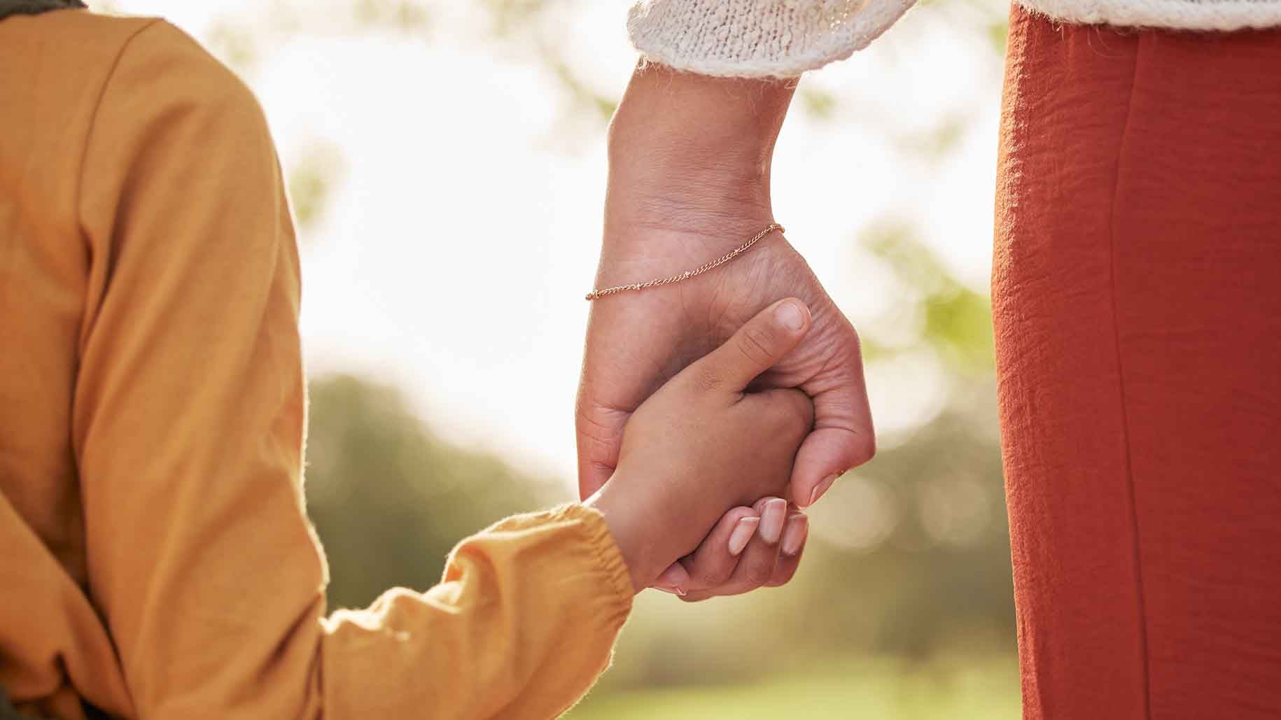 A close-up of a mother holding her child's hand. 