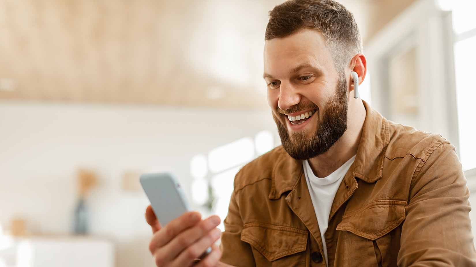 A man smiling while holding a phone.