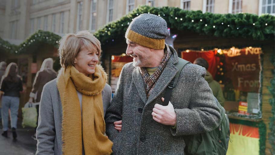 A couple smiling walking through a Festive market in Newcastle. 