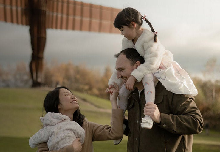 Husband and wife with their two children smiling. 